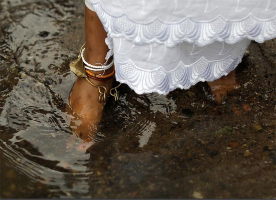 امرأة تتجول في الماء على طول شاطئ جزيرة راندال على النهر الشرقي أثناء احتفال مياه شروق الشمس