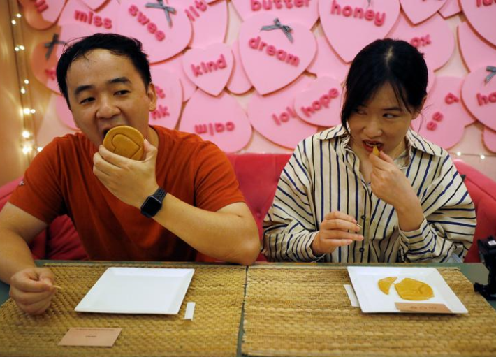 وانغ تشن، 32 عاما، وتشانغ تشي، 27 عاما، يجربان أيديهما في تحدي قرص العسل الذي ظهر في المسلسل الجديد ل Netflix Squid Game، في مقهى براون باتر في سنغافورة