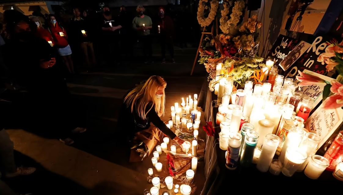 امرأة تضيء شمعة تكريما لهتشينز يوم الأحد في بوربانك