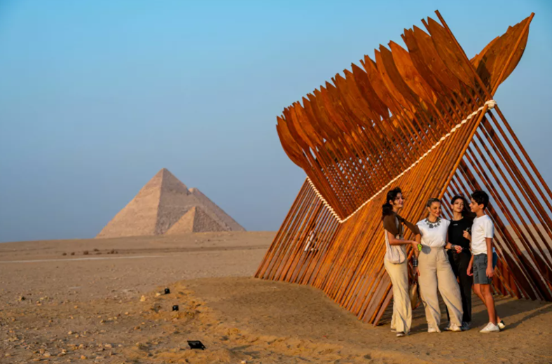 سياح يقفون بالقرب من تركيب فني بعنوان بطرخ للفنان المصري معتز نصر