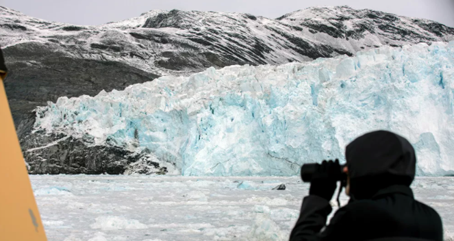 سائح يلتقط صوراً للجبل الجليدي إيكي في شمال إيلوليسات