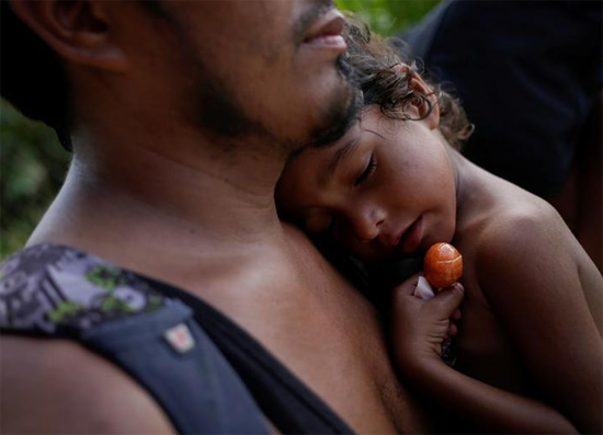 فتاة مهاجرة هندوراسية مريضة بالحمى ، أليسون ، 4 سنوات ، تحمل مصاصة بينما كان والدها يحملها