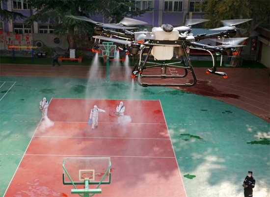 طائرة بدون طيار ترش مطهرًا على متطوعين يقومون بتطهير مدرسة بالصين