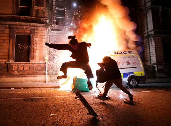 أحد المتظاهرين يفر أمام سيارة شرطة محترقة  في بريستول  بريطانيا