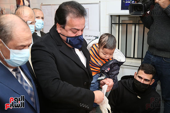 وزير الصحه والتعليم العالم يحمل طفل قبل التطعيم