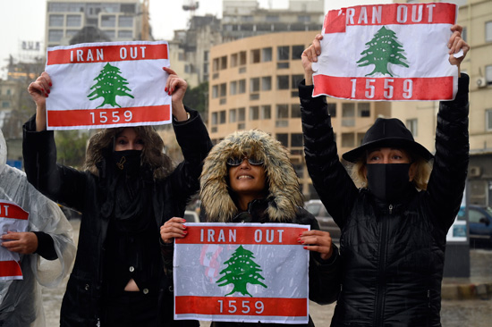 نساء لبنانيات يرفعن لافتات تُظهر العلم الوطني