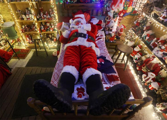 رجل يرتدي زي بابا نويل يقرية عيد الميلاد مزينة بآلاف الأضواء  في هام ميل بلجيكا