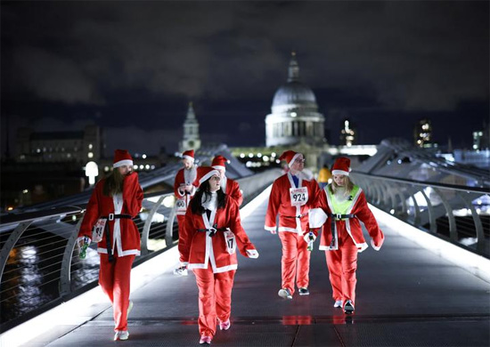 أشخاص يرتدون زي بابا نويل يمشون فوق جسر الألفية فى بريطانيا