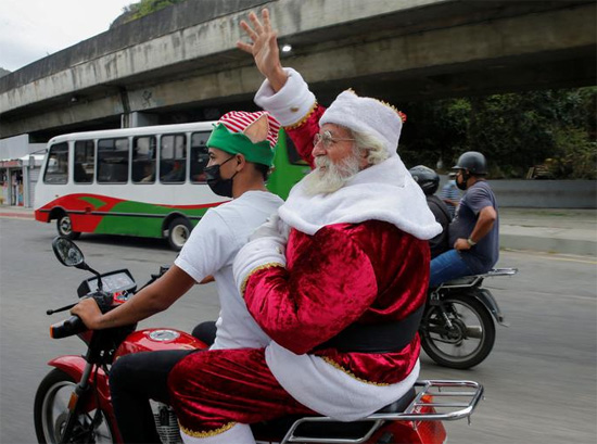 رجل يرتدي زي بابا نويل يركب دراجة نارية أثناء توزيع لعبة عيد الميلاد فنزويلا