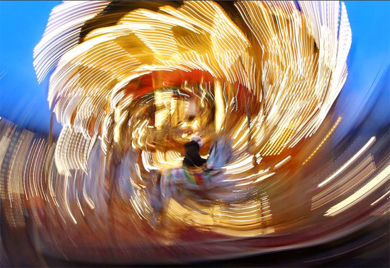 طفل يرتدي قناعًا واقيًا يركب دائريًا في سوق الكريسماس