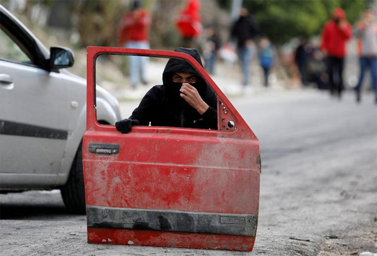 متظاهر فلسطيني يختبئ خلف باب سيارة متظاهر فلسطيني يختبئ خلف باب سيارة