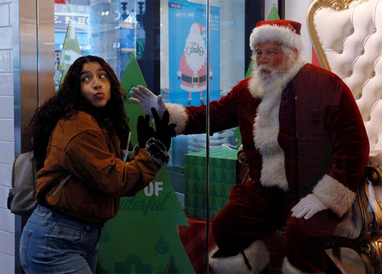 فتاة تلتقط صورة مع رجل يرتدي زي بابا نويل