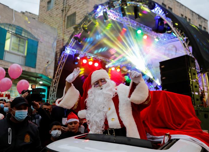 فلسطيني يرتدي زي بابا نويل يشير خلال احتفال في بيت لحم بالضفة الغربية