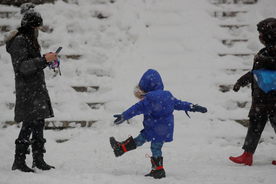 طفل يلهو مع والدية بالثلوج