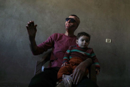 الناطر يحمل طفله في منزله في مدينة غزة