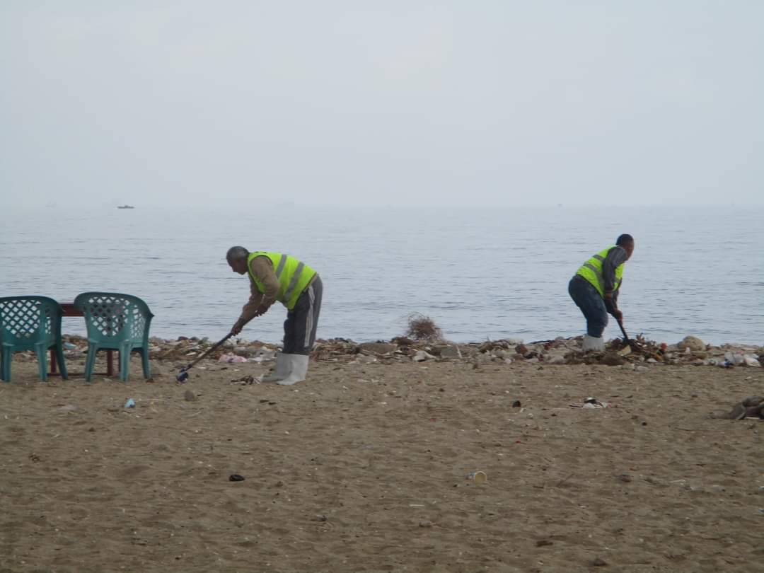 عمال النظافة أثناء تنظيفهم شاطئ بورفؤاد