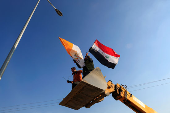 متطوعون مسيحيون يرفعون علم العراق والفاتيكان وهم يزينون الشوارع (1)