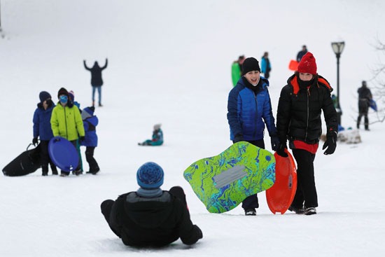 مجموعة أطفال يلعبون بالزلاجات بعد تساط الثلج