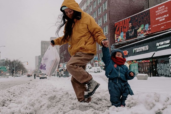 طفل مع والدته يسيران في الشوارع المغطاة بالثلوج