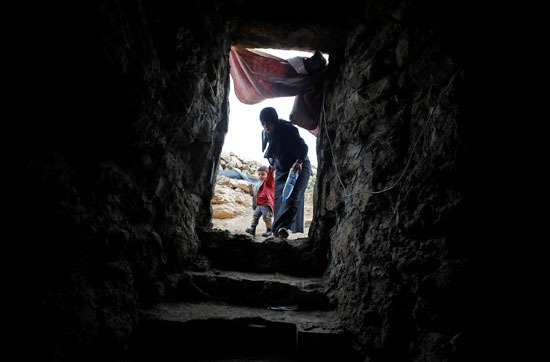 امرأة فلسطينية تدخل كهفًا على أحد التلال