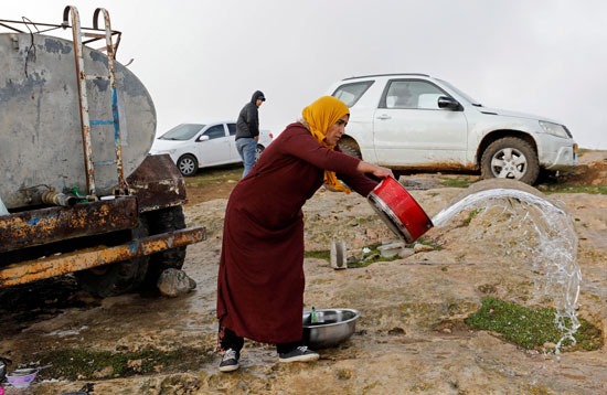 امرأة فلسطينية تغسل الأواني خارج كهف على أحد التلال