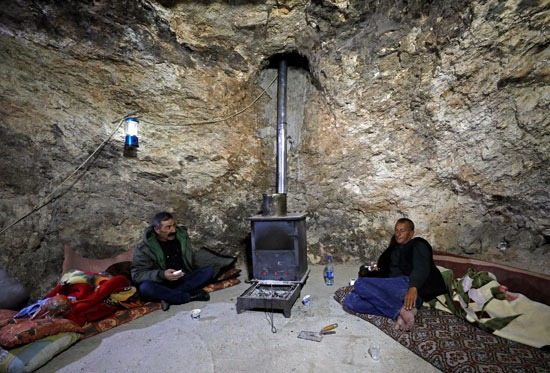 رجل فلسطيني يجلس في كهف على جانب التل مع شقيقه