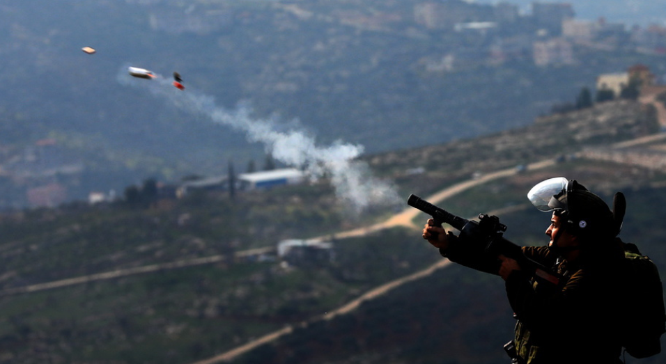 جندي صهيوني يطلق الغاز على الفلسطينيين
