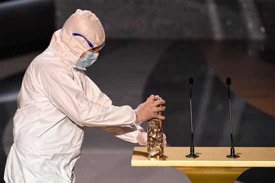 رجل يرتدي بدلة واقية يضع جائزة سيزار على المنصة خلال حفل توزيع جوائز سيزار