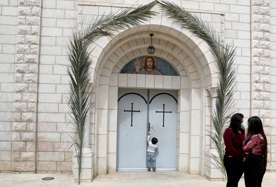 طفل فلسطيني يحاول فتح باب كنيسة خلال القداس