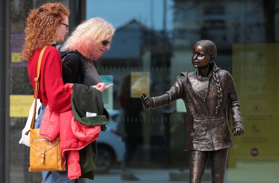 نساء ينظرن إلى تمثال للناشطة السويدية