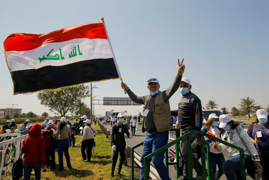 رجل يحمل العلم العراقي بينما ينتظر وصول البابا فرنسيس