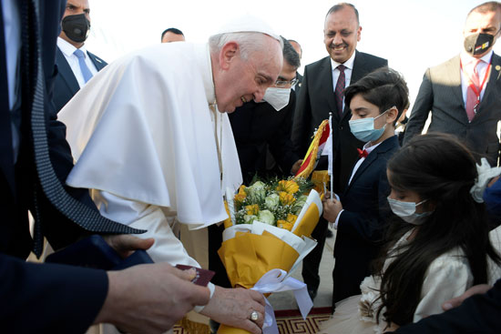 البابا فرانسيس يتلقى باقة زهور أثناء لقاءه بالمرجع الشيعي علي السيستاني