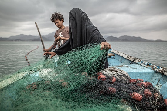 فاطمة وابنها يحضران شبكة صيد في خليج باليمن