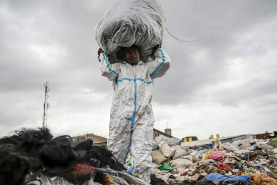 رجل يرتدي بدلة واقية وجدها في القمامة ينظف الشعر الاصطناعي في داندورا