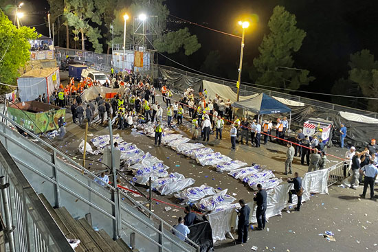 مسؤولون أمنيون إسرائيليون وعمال إنقاذ يقفون حول جثث الضحايا
