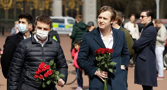رجلين يستعدان لترك الزهور أمام بوابة قصر باكنجهام