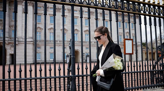 امرأة تستعد لوضع باقة من الزهور بعد إعلان وفاة الأمير فيليب