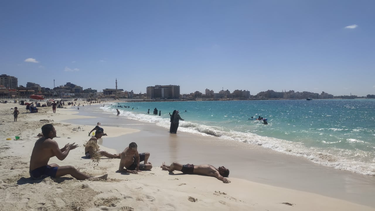 شباب واطفال يستمتعون بالسباحة واللعب بالرمال على شواطئ مطروح