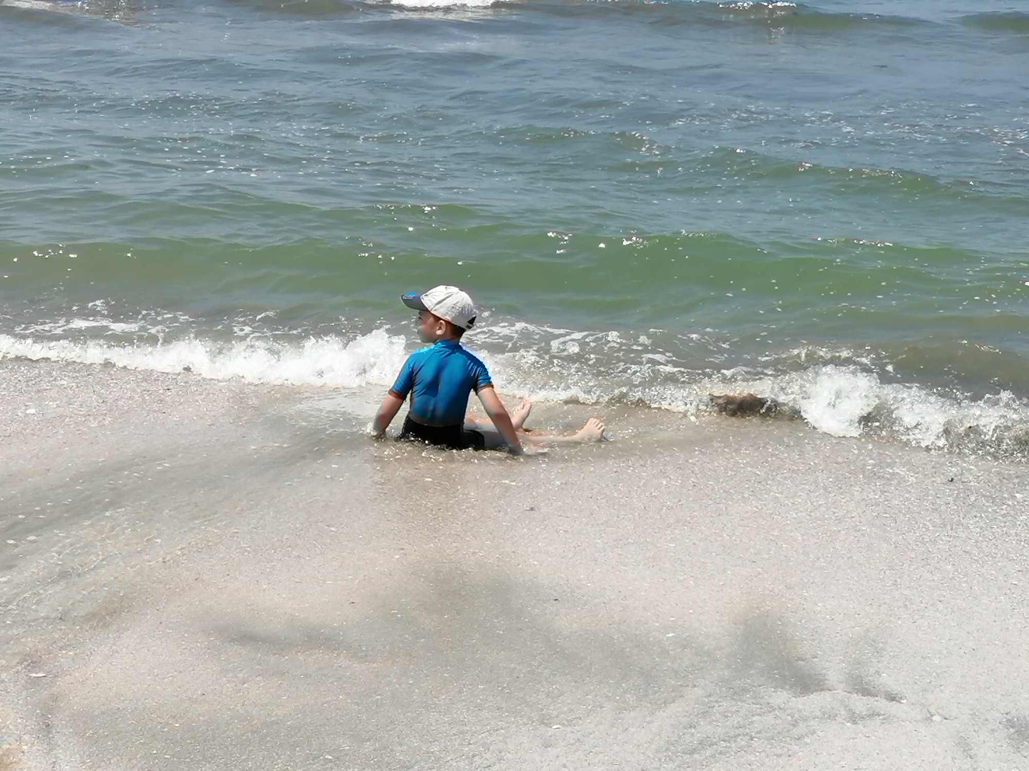 احد الأطفال يلعب برمال الشاطئ