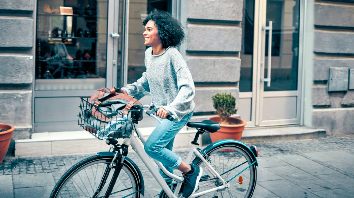 Woman-Riding-Rented-Bicycle-In-A-City.-Cycling-and-smiling-1296x728-header-1296x728