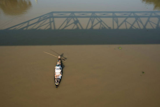 يمر قارب خشبي تقليدي على نهر سورما تحت جسر كين