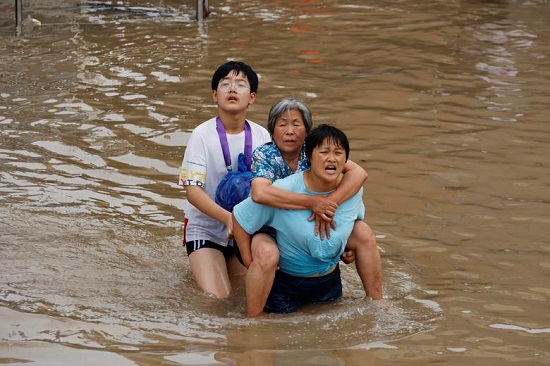 امرأة تحمل امرأة مسنة وهي تشق طريقها عبر مياه الفيضانات