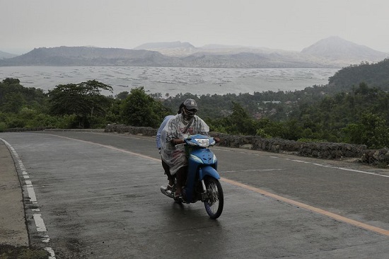 رجل يركب دراجته النارية يمر بجوار بركان تال في مقاطعة باتانجاس.