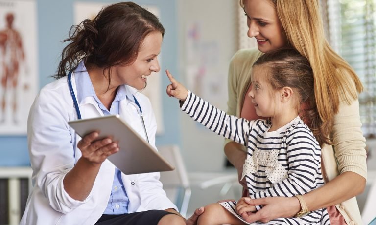 girl-on-mothers-lap-reaches-towards-doctor-768