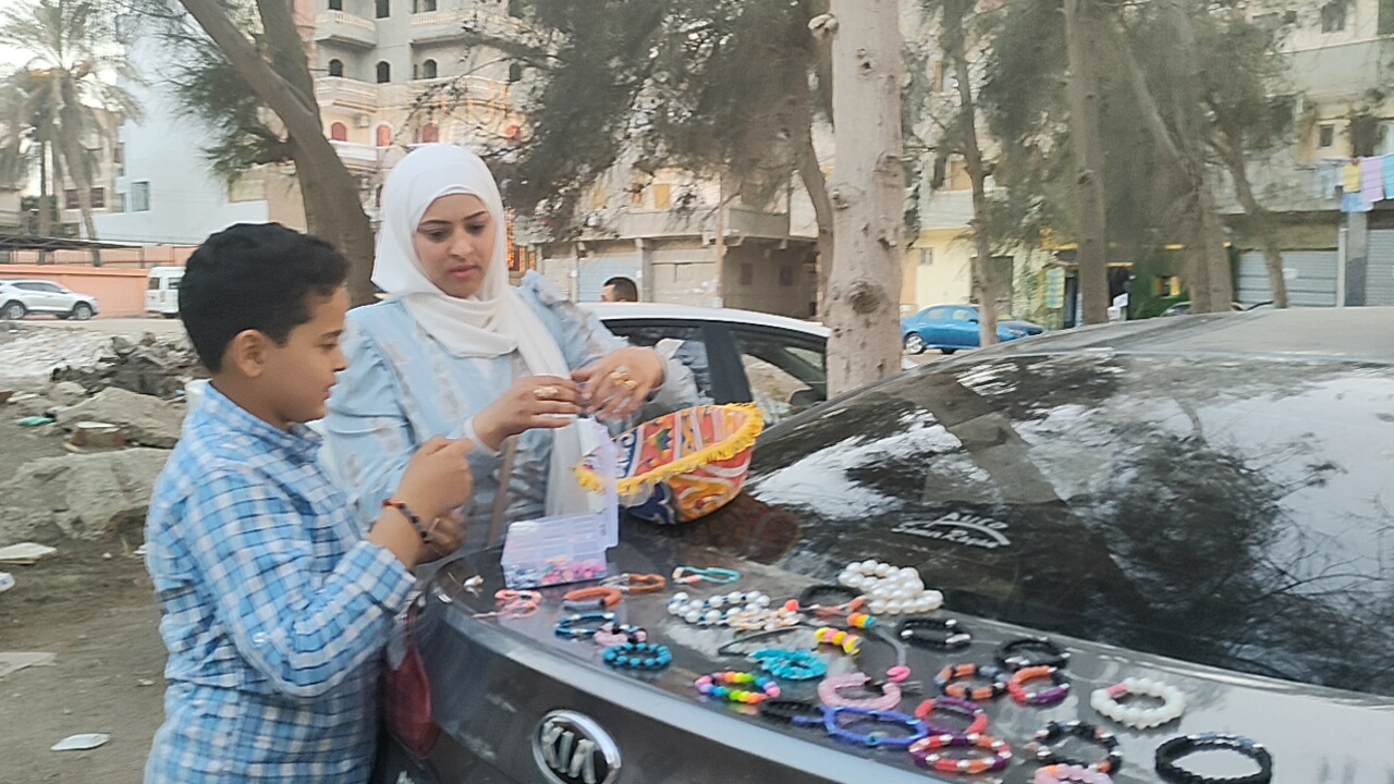 عبد الله ووالدته خلال بيعه للاكسسوارات والحظاظات فى الشارع