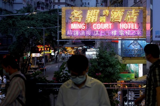 أشخاص يمشون أمام لافتة نيون في هونج كونج