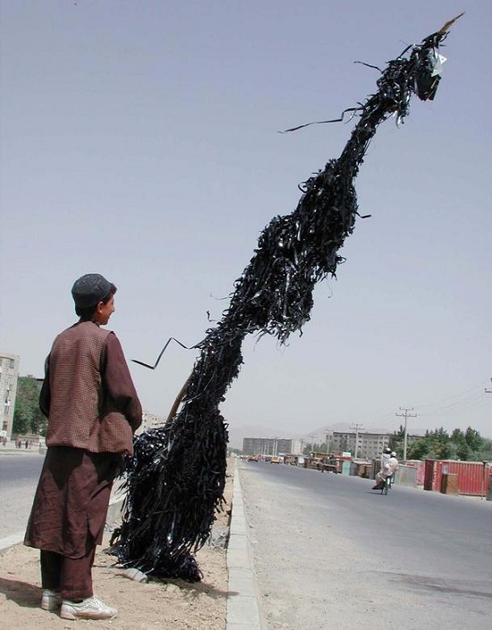 طفل أفغاني ينظر إلى عمود معلق بمئات من أشرطة الفيديو والموسيقى المدمرة