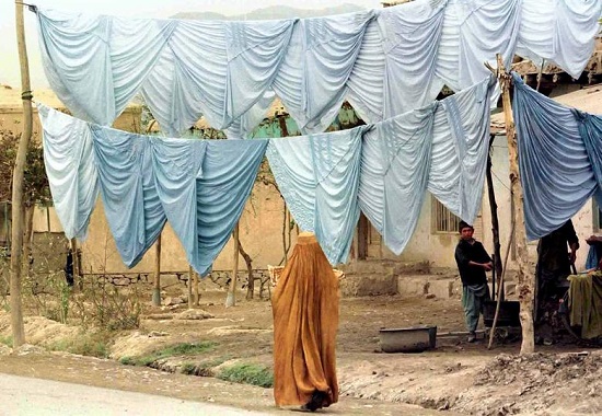 امرأة أفغانية ترتدي البرقع تمر أمام متجر - 1996