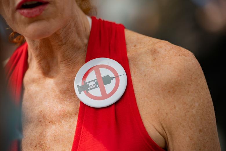 امراة تحتج على أخذ اللقاح بارتداء دبوس عليه شعار اللقاح