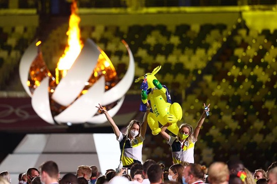 أعضاء الفريق من أستراليا يحملون تعويذة قابلة للنفخ أمام الشعلة الأولمبية